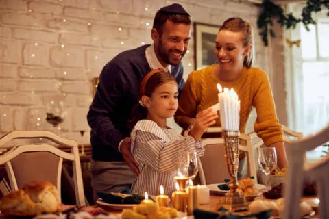 Family of three lighting menorah