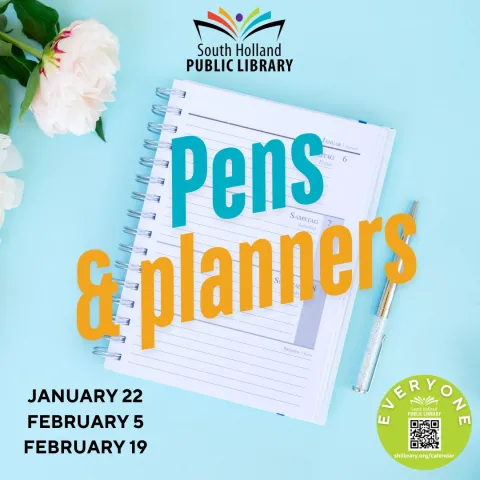 Spiraled Planner and Pen on Blue Background with White Flowers behind