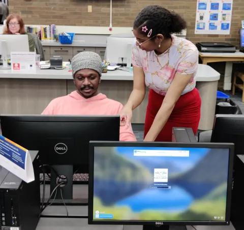 A helpful, and dare I might say it, beautiful Librarian helping out a dear Patron in need of technology help :^)