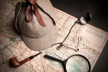 Sherlock Holmes hat, pipe, and watch resting on a map