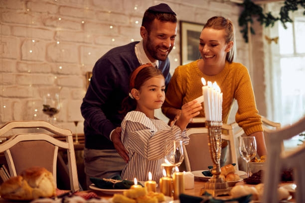 Family of three lighting menorah