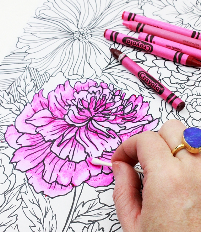 Someone using a pink crayon to color a flower